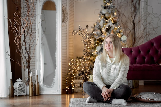 fille assise près du sapin de noël