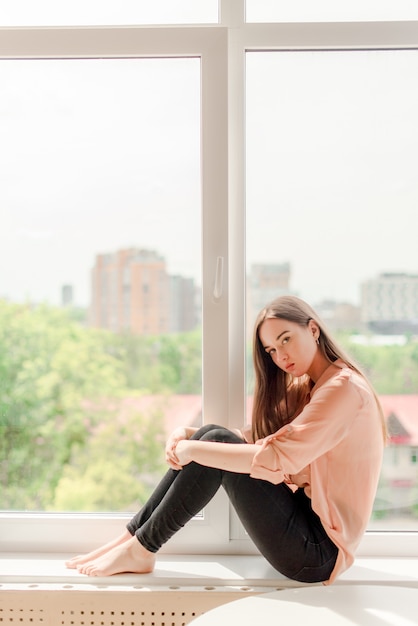 Fille assise près de la fenêtre