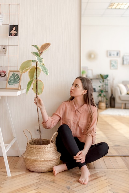 Photo fille assise près d'une plante à la maison