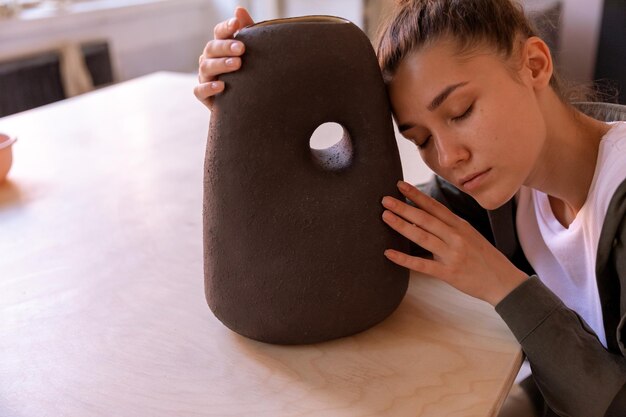 Photo une fille assise avec un vase en argile objet en argile sur une masterclass de poterie