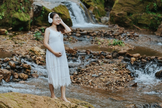 Fille assise sur le ventre en écoutant de la musique dans la forêt