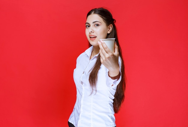 Fille assistante offrant une tasse de café.