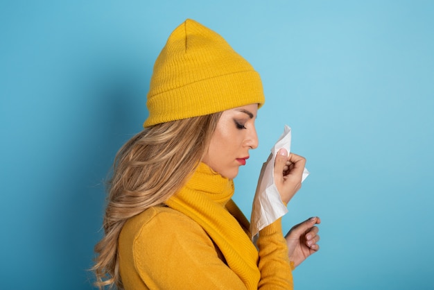 La fille a attrapé froid et s'essuie le nez.