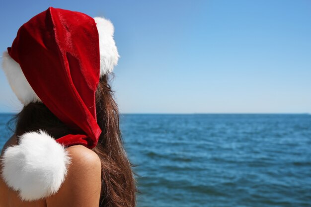 Fille au bonnet de Noel sur la plage. Notion de Noël