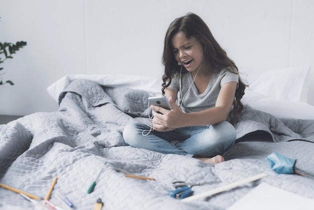 Une fille au casque blanc qui s'assied sur le lit.