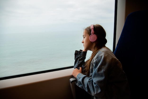 Une fille au casque dans un train regarde par la fenêtre. Périple.