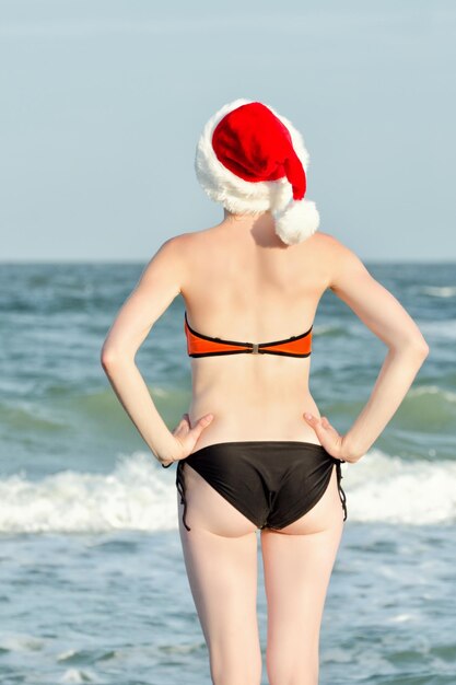 Fille au chapeau du Père Noël au bord de la mer Vue arrière