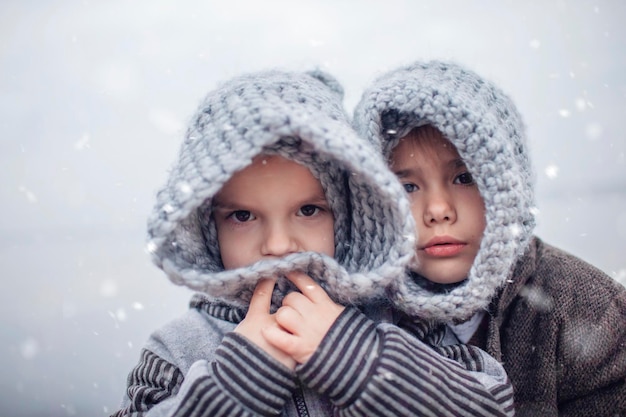 Fille au chapeau gris tricoté serrant son petit frère congelé