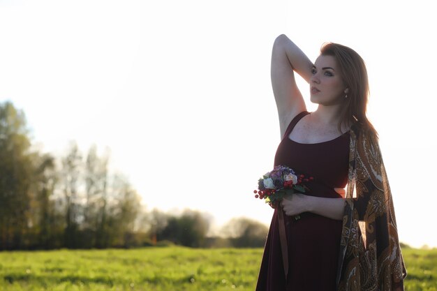 Une fille au chapeau lors d'une promenade dans le parc. Une fille avec un panier marche au printemps. La fille marche le long de la route au coucher du soleil.