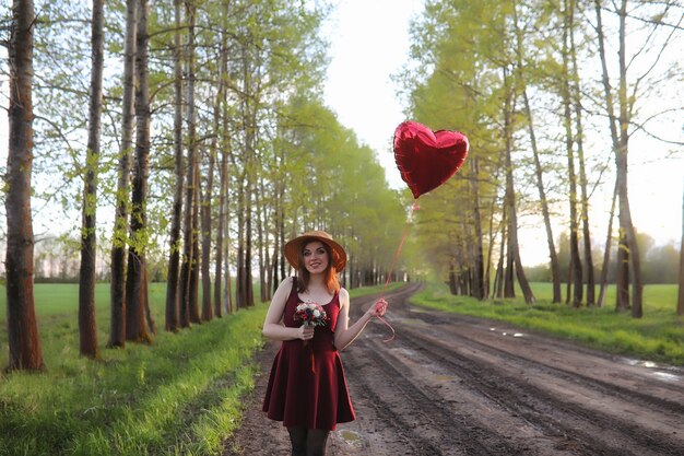 Une fille au chapeau lors d'une promenade dans le parc. Une fille avec un panier marche au printemps. La fille marche le long de la route au coucher du soleil.