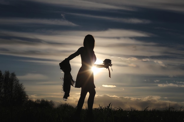 Une fille au chapeau lors d'une promenade dans le parc. Une fille avec un panier marche au printemps. La fille marche le long de la route au coucher du soleil.