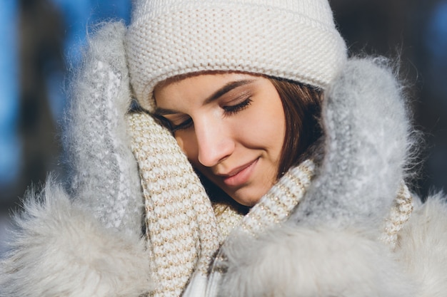 Fille au chapeau et mitaines souriant en hiver