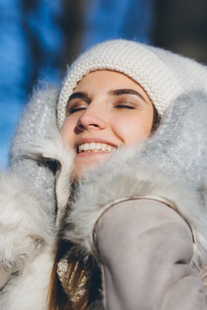 Fille au chapeau et mitaines souriant en hiver