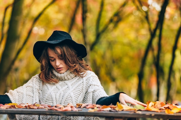 Une fille au chapeau noir avec un charmant sourire. Fille dans le parc sur fond de nature automnale.