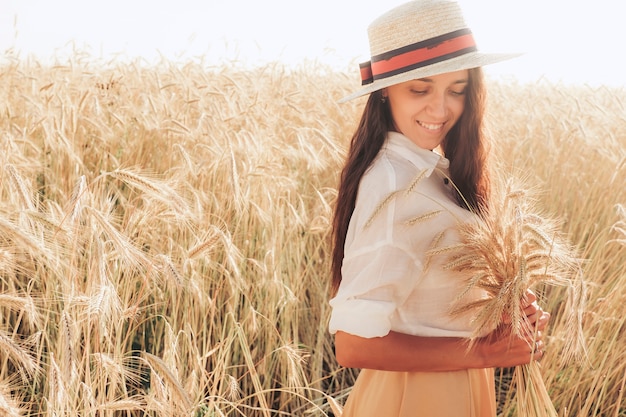 La fille au chapeau de paille sourit en fermant les yeux.