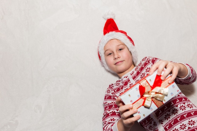 Fille au chapeau de père Noël avec un cadeau sur fond blanc