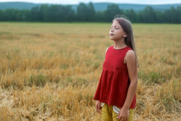 Fille au chapeau et en robe rouge prend un bain de soleil sur l'herbe verte Pas de visage Photo de haute qualité