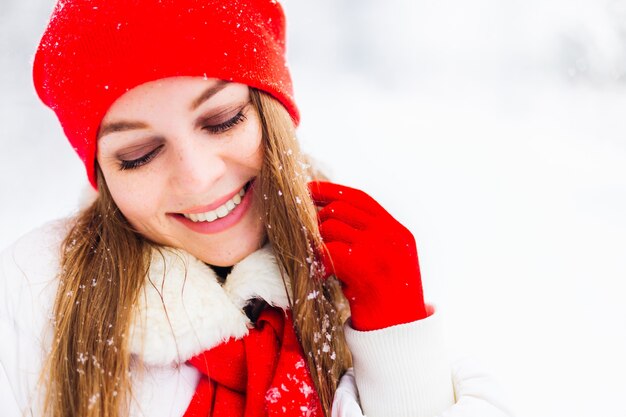 Fille au chapeau rouge et écharpe sourit le jour de l'hiver