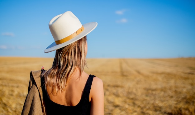 Fille au chapeau de style au champ de blé de la campagne