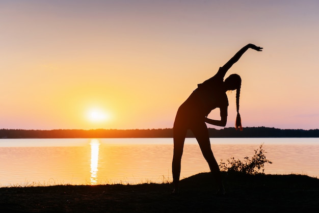 Fille au coucher du soleil au bord du lac