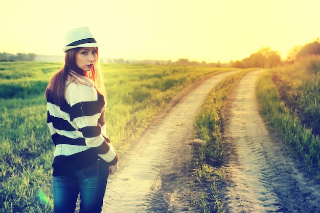 Fille au coucher du soleil sur le terrain de la mode chapeau