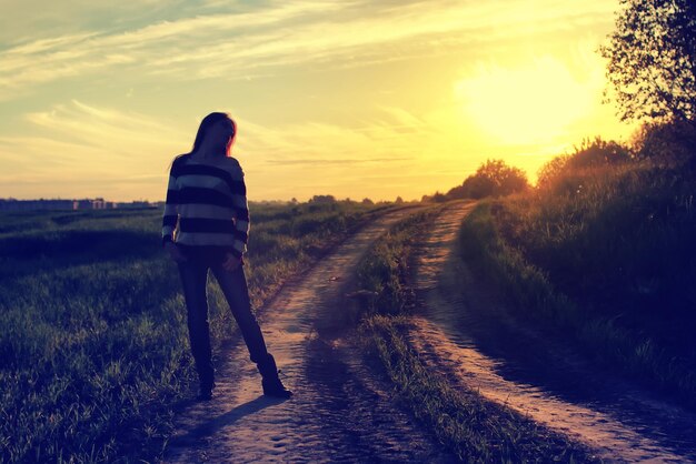 Fille au coucher du soleil sur le terrain de la mode chapeau