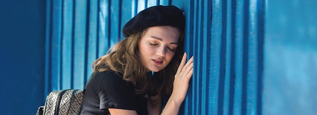 La fille au mur bleu en béret et jupe Française élégante à l'ombre de la ville