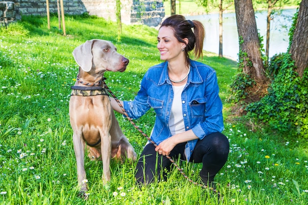 Fille au parc avec chien Weimaraner