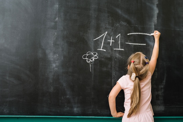 Fille au tableau noir en classe de mathématiques