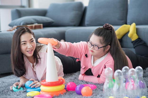 Fille autiste. Fille autiste s'amusant à jouer à des jouets à la maison avec sa mère.