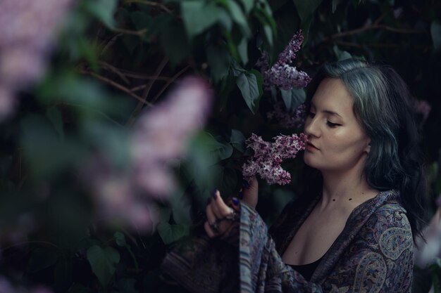 Photo une fille aux cheveux bleus renifle le lilas photo comme une photo