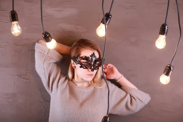 Une fille aux cheveux blonds dans un masque noir pose