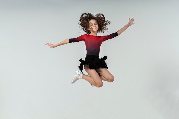 Photo une fille aux cheveux bouclés engagée dans la danse de salle de bal saute avec des émotions joyeuses et malicieuses