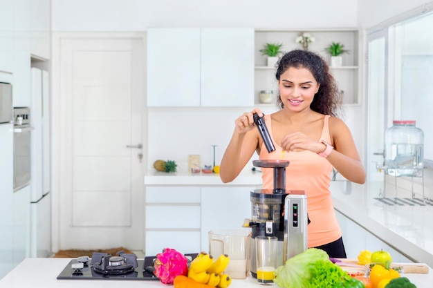 Fille aux cheveux bouclés faisant un jus sain à la maison