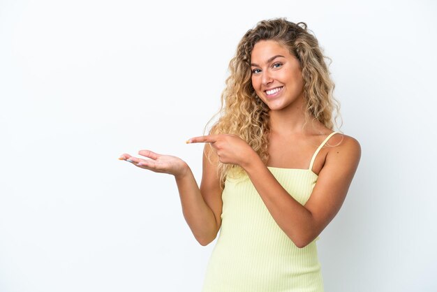 Fille aux cheveux bouclés isolé sur fond blanc tenant un fond imaginaire sur la paume pour insérer une annonce