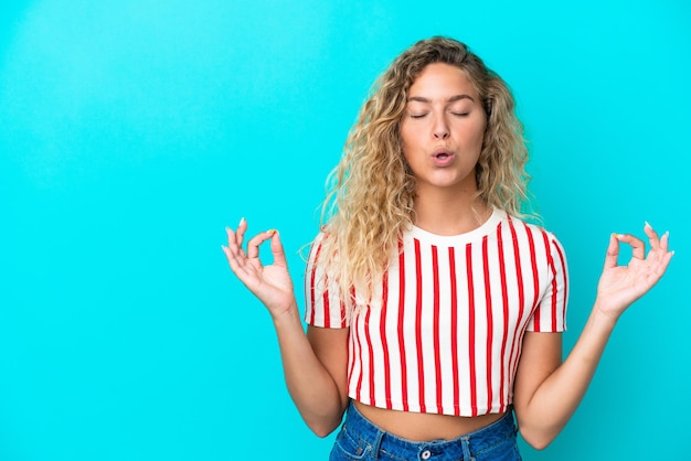 Fille aux cheveux bouclés isolé sur fond bleu dans une pose zen