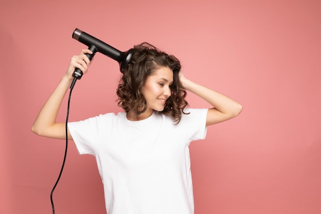 Une fille aux cheveux bouclés avec sèche-cheveux et diffuseur d'air après la coiffure