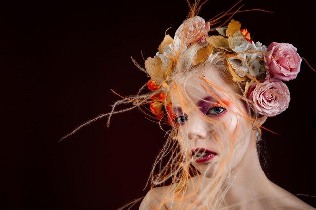 Une fille aux cheveux bouclés vifs et des fleurs dans la tête. Objet d'art. Fée fille aux fleurs