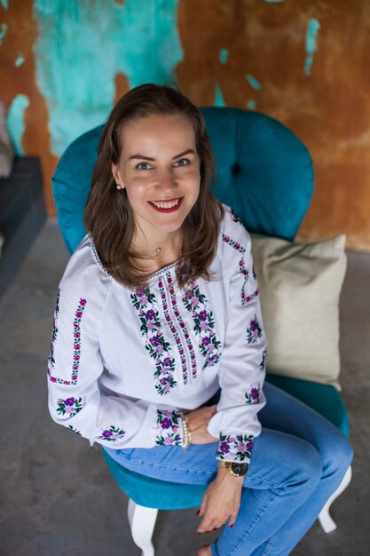 Fille aux cheveux bruns est assise sur une chaise bleue