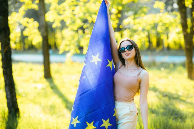 une fille aux cheveux bruns posant avec le drapeau de l'union européenne