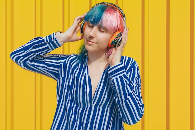 Fille aux cheveux colorés, écouter de la musique avec des écouteurs