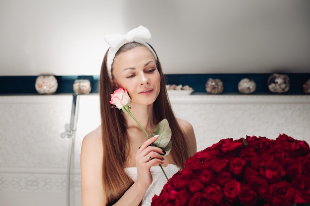 Fille aux cheveux longs assis sur le bain après la douche du matin