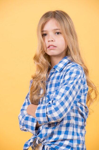 Fille aux cheveux longs blonds en chemise à carreaux bleu pose