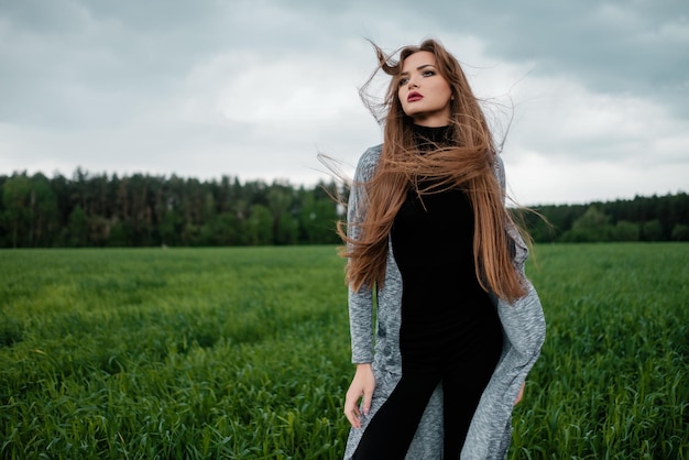 Fille aux cheveux longs debout dans le champ dans le vent Soncept de liberté et de passion