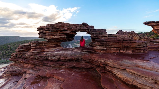 une fille aux cheveux longs est assise au-dessus d'une fenêtre de la nature dans le parc national de kalbarri en australie occidentale