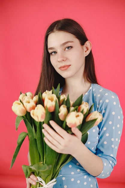 Fille aux cheveux longs. Femme avec un bouquet de fleurs. Dame en robe bleue.