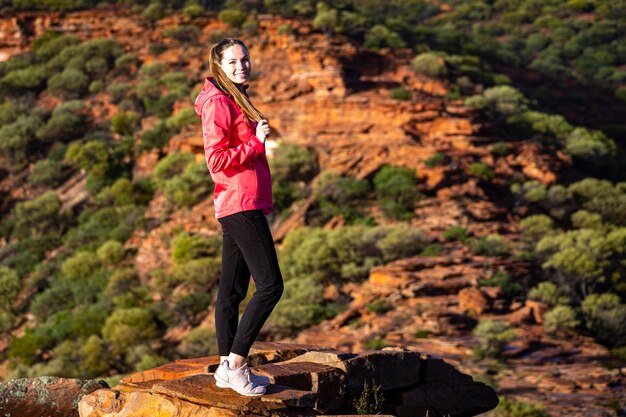 fille aux cheveux longs se promène le long d'une crête sur les roches rouges du parc national de kalbarri dans l'ouest de l'australie