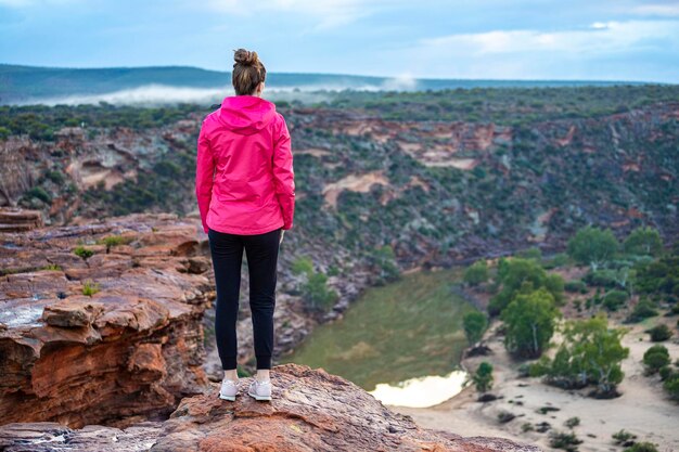 fille aux cheveux longs se promène le long d'une crête sur les roches rouges du parc national de kalbarri dans l'ouest de l'australie