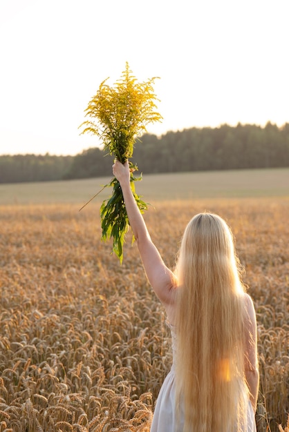 Une fille aux cheveux longs tenant un bouquet de fleurs Le concept de liberté prospérité fertilité