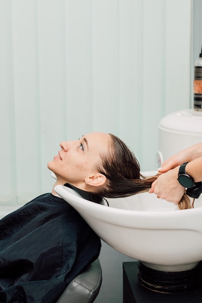 Une fille aux cheveux mouillés est assise la tête dans l'évier